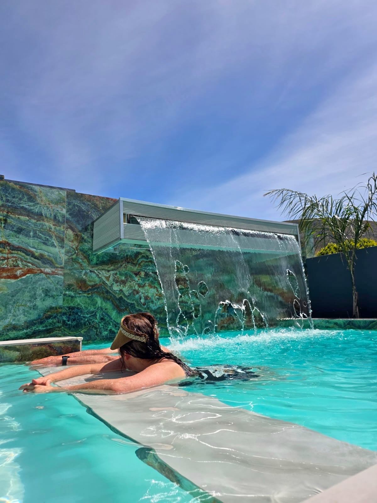 Water falling against the green onyx wall into the pool